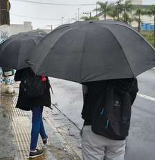 Pedestres se protegem da chuva na Avenida Interlagos, no Jardim Consórcio, zona sul de São Paulo, nesta sexta-feira, 2 de outubro de 2026 Foto: MARCO AMBROSIO/ATO PRESS/ESTADÃO CONTEÚDO