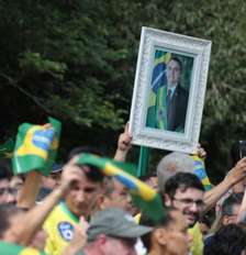 Apoiadores de Flávio Bolsonaro acenam com bandeiras do Brasil e quadro de Jair antes de carreata em Santa Bárbara d'Oeste Foto: Felipe Rau/Estadão