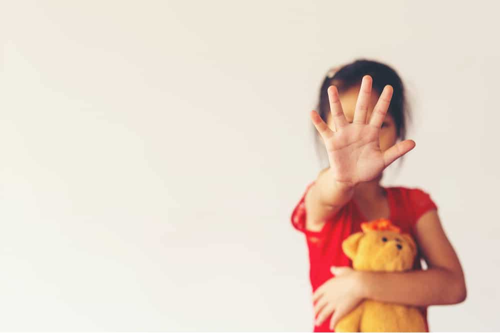 Imagem mostra uma criança com a mão à frente de seu rosto, que está desfocado, simbolizando campanhas de combate ao abuso infantil